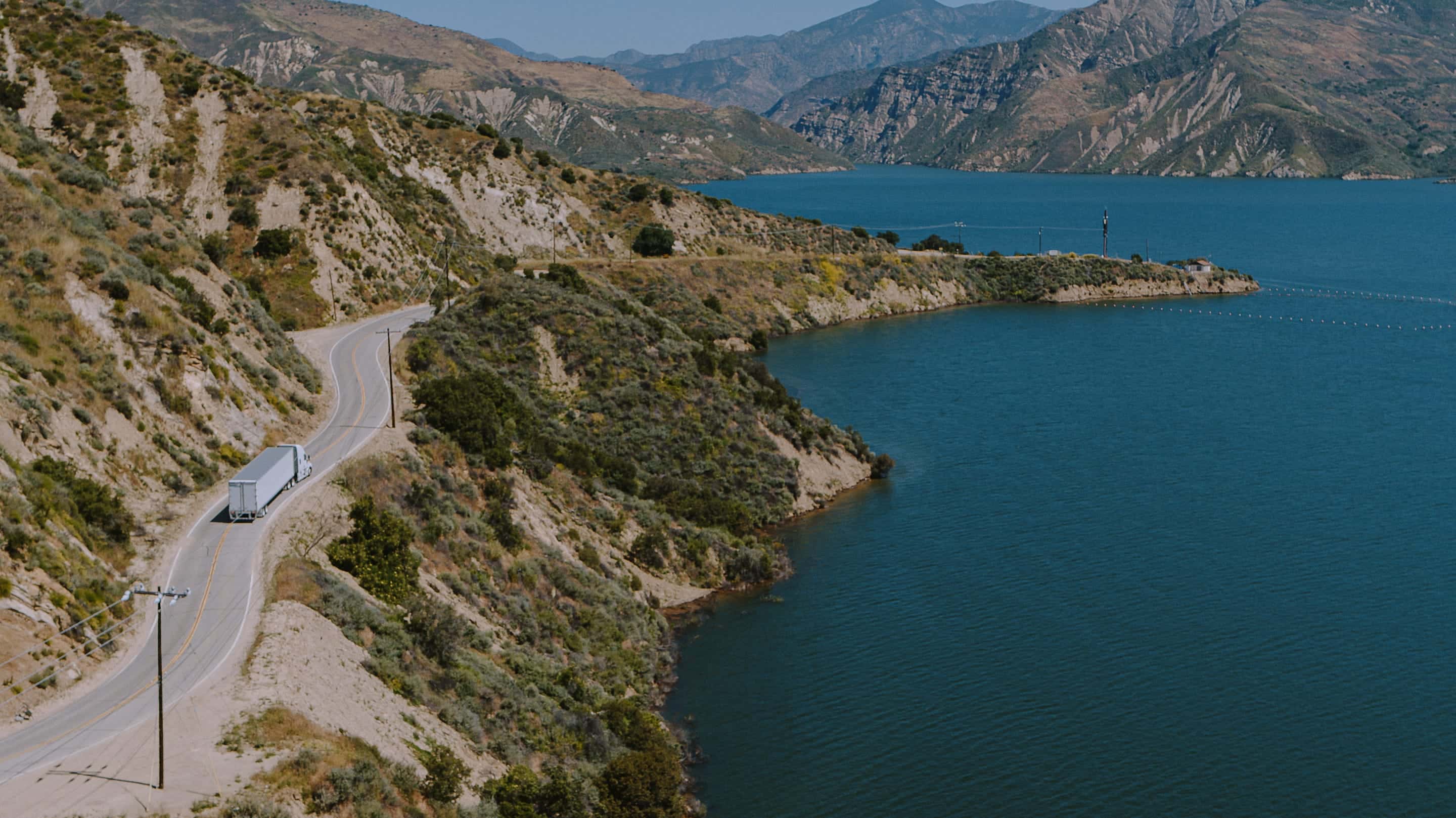 truck on mountain road by lake