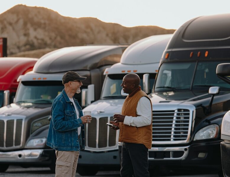 two men talking in front of trucks